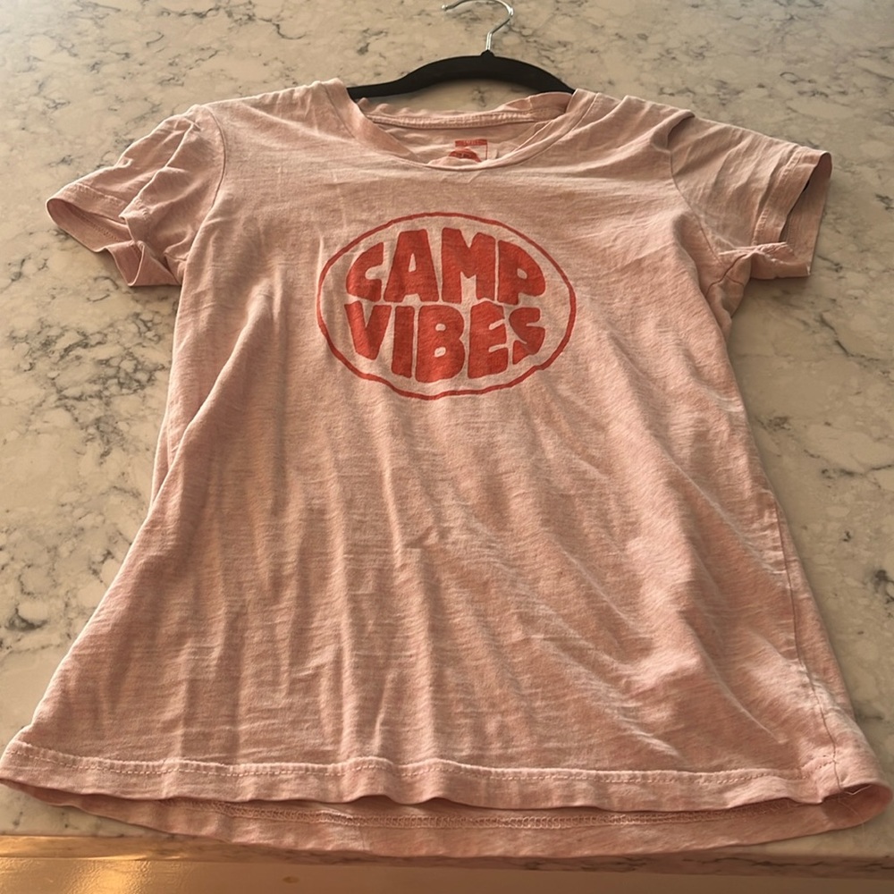 This is a pink shirt that says camp vibes. It’s very cute.
